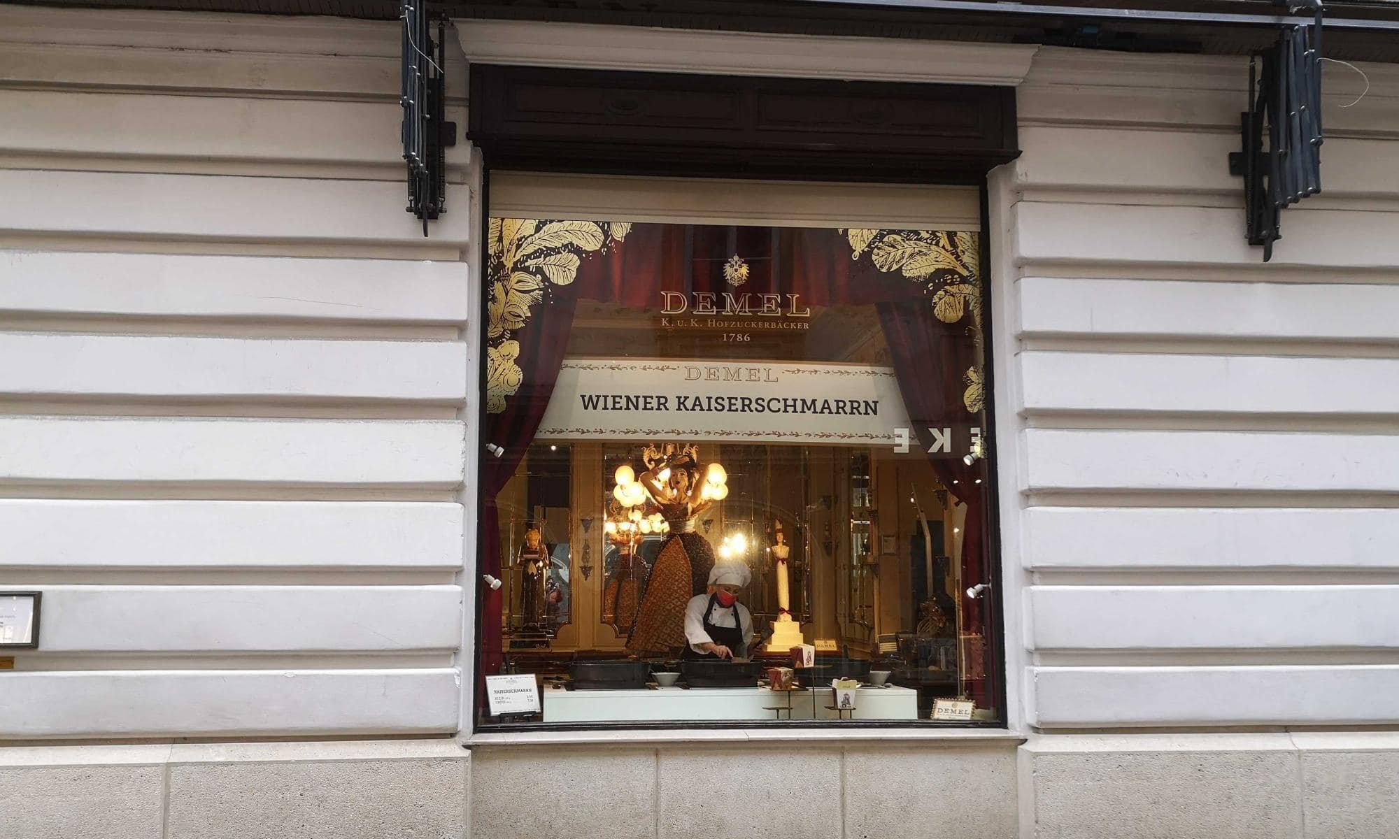 Schaufenster der traditionsreichen Wiener Konditorei Demel, in dem ein Koch Kaiserschmarrn zubereitet