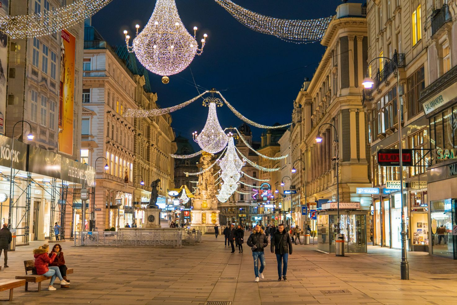 Nächtliche Ansicht der Kärntner Straße in Wien, Österreich, geschmückt mit eleganten Kronleuchtern und festlicher Beleuchtung.