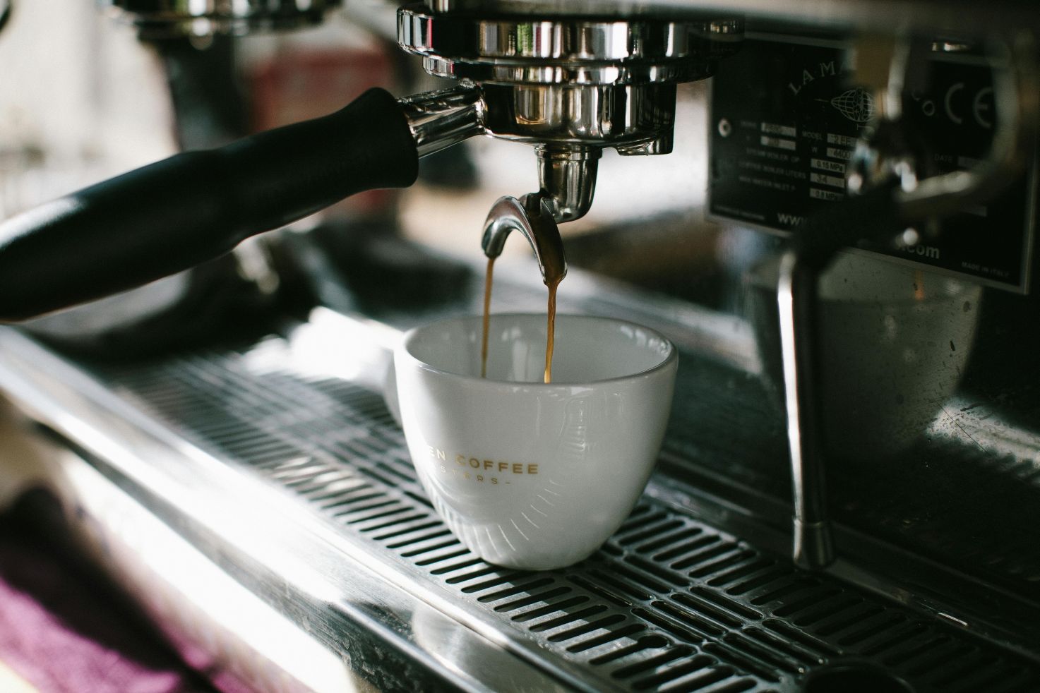 Espressomaschine, die frischen Kaffee in eine weiße Tasse gießt